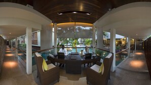 A reception area with a pool view, wicker furniture, and a modern ceiling design. - Dhevatara Beach Hotel & Spa (Praslin Island)
