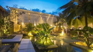 A serene courtyard with a reflective pool, palm trees, and warm ambient lighting. - Dhevatara Beach Hotel & Spa (Praslin Island)