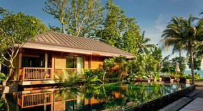 A resort with a pool, wooden deck, and tropical vegetation.