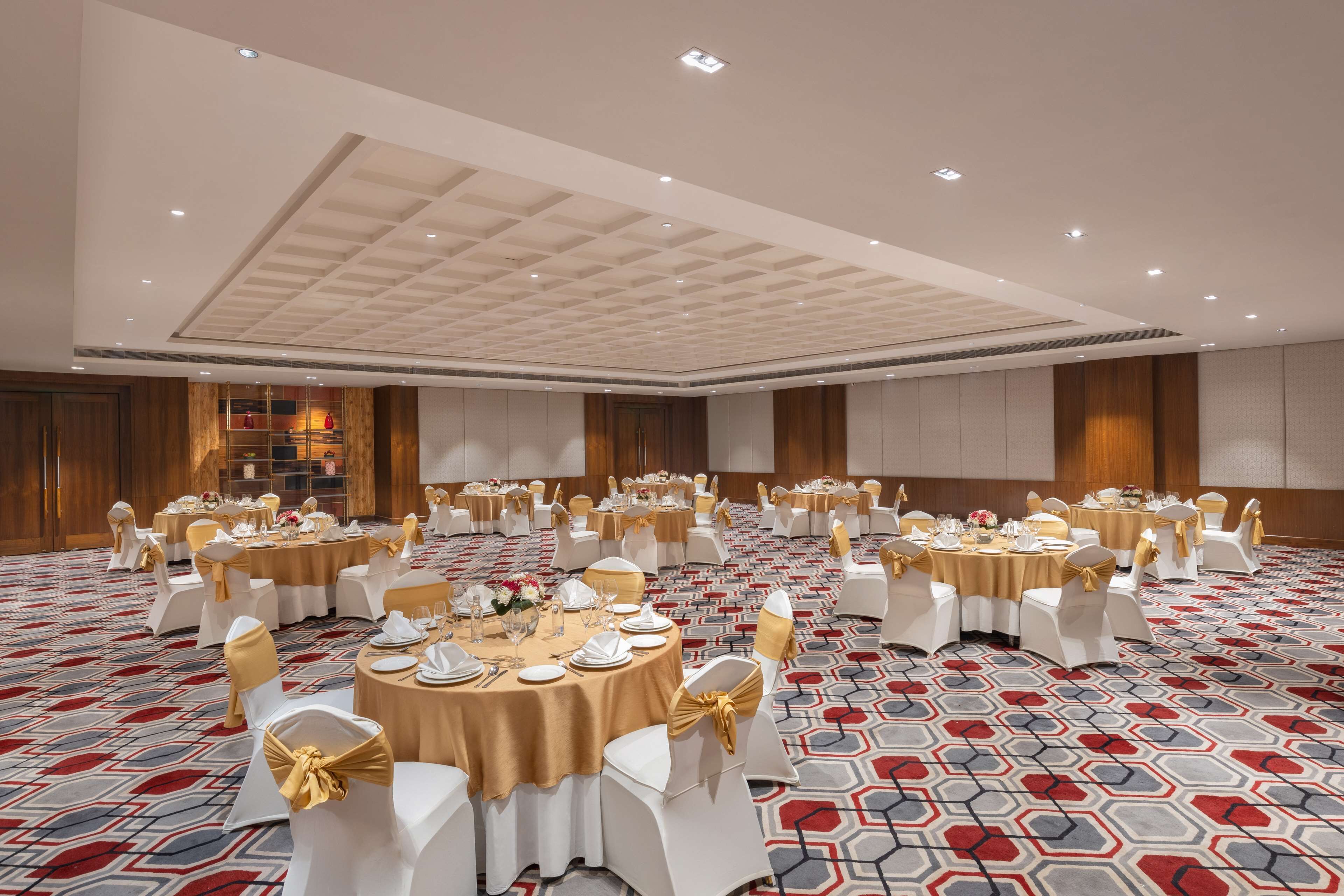 A banquet hall with round tables set for dining, white chairs, and gold sashes.
