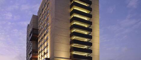 A modern hotel building with a prominent "DOUBLETREE BY HILTON" sign, featuring a sleek, vertical design with illuminated windows and a spacious entrance area.