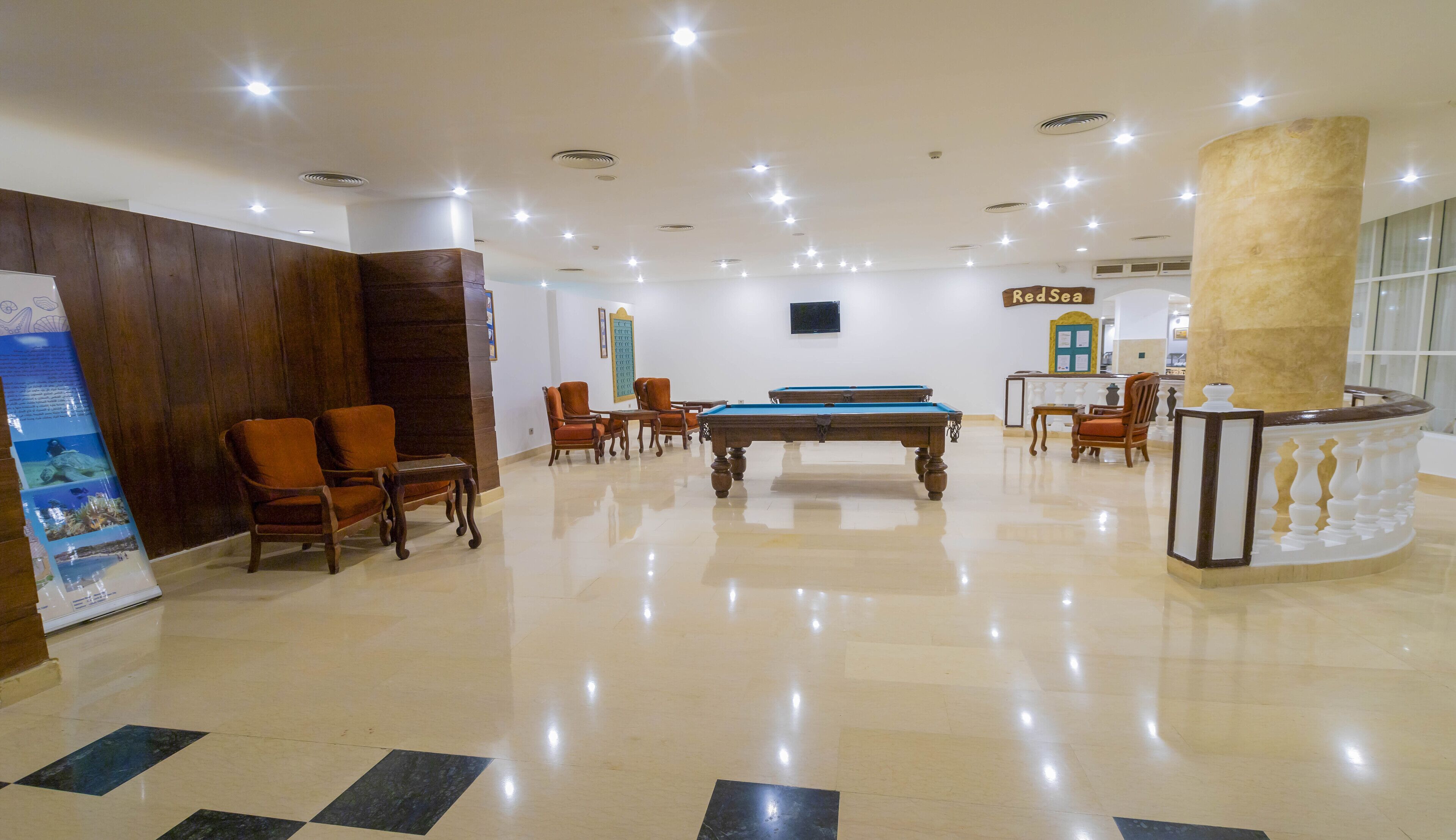A spacious lobby with a pool table, comfortable seating, and a reception area.
