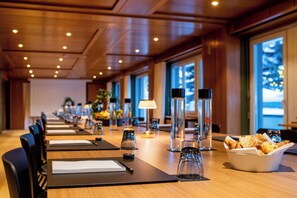 Un salón de conferencias con largas mesas, sillas y una mesa de buffet con pastelería.