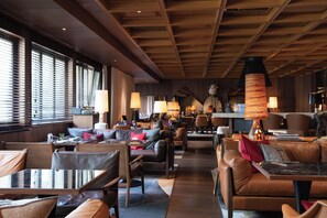 A spacious lounge area with leather seating, wooden tables, and ambient lighting. - Schweizerhof Zermatt (Zermatt)