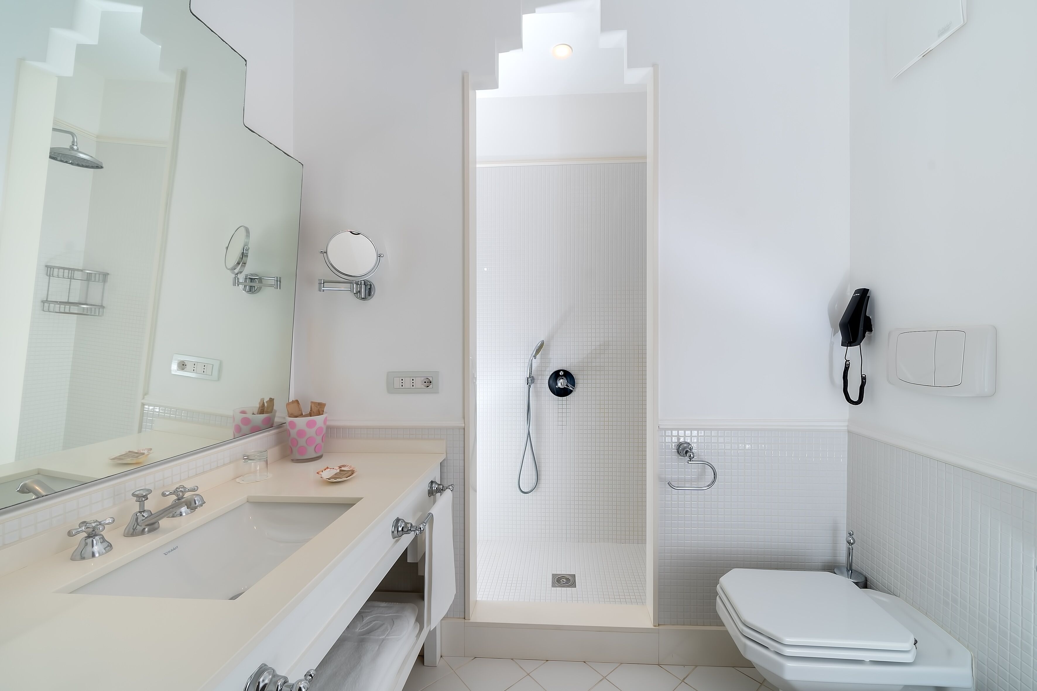 Un baño moderno con un espejo grande, lavamanos, inodoro y zona de ducha.