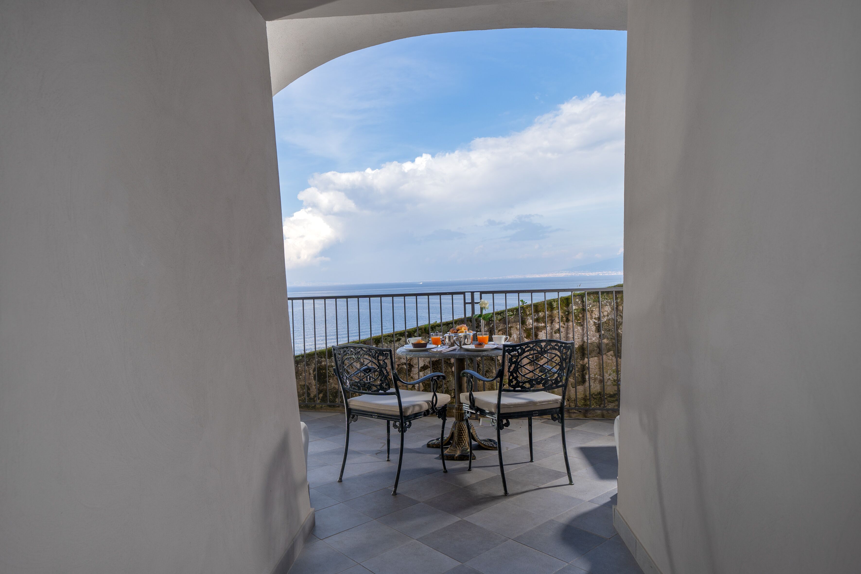 Un balcon avec une table et des chaises, offrant une vue sur la côte.