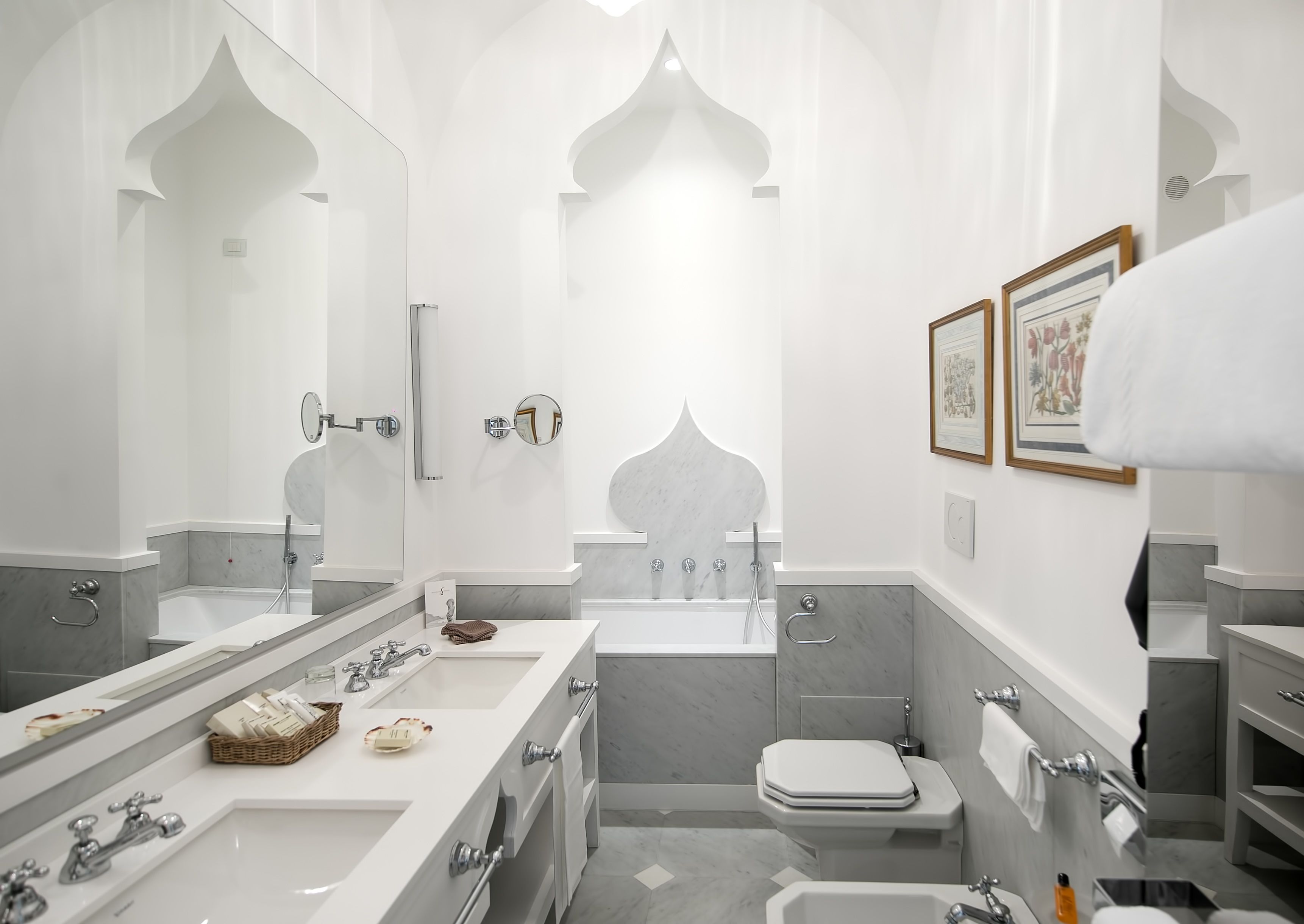 A modern bathroom with two sinks, a bathtub, and a toilet.