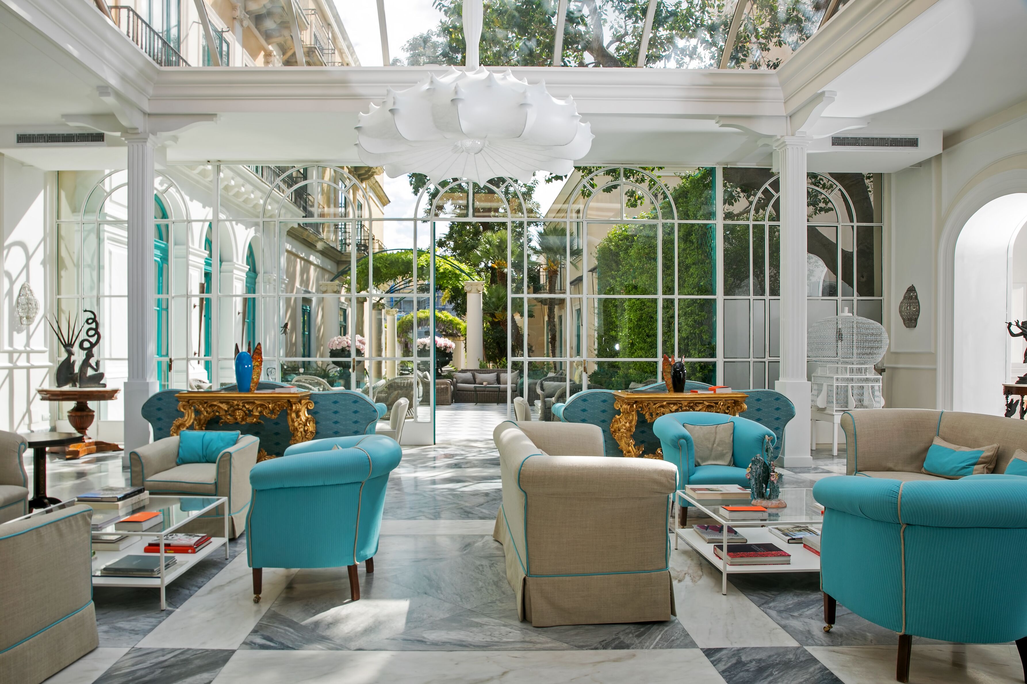 Un salón amplio y elegantemente amoblado, con techos altos y ventanas grandes que ofrecen vistas al exterior.