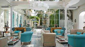 Un salón amplio y elegantemente amoblado, con techos altos y ventanas grandes que ofrecen vistas al exterior.