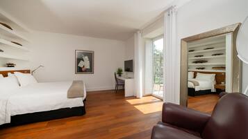 Une chambre d’hôtel moderne avec un grand lit, un bureau et une chaise. Une grande fenêtre offre une vue sur l’extérieur.