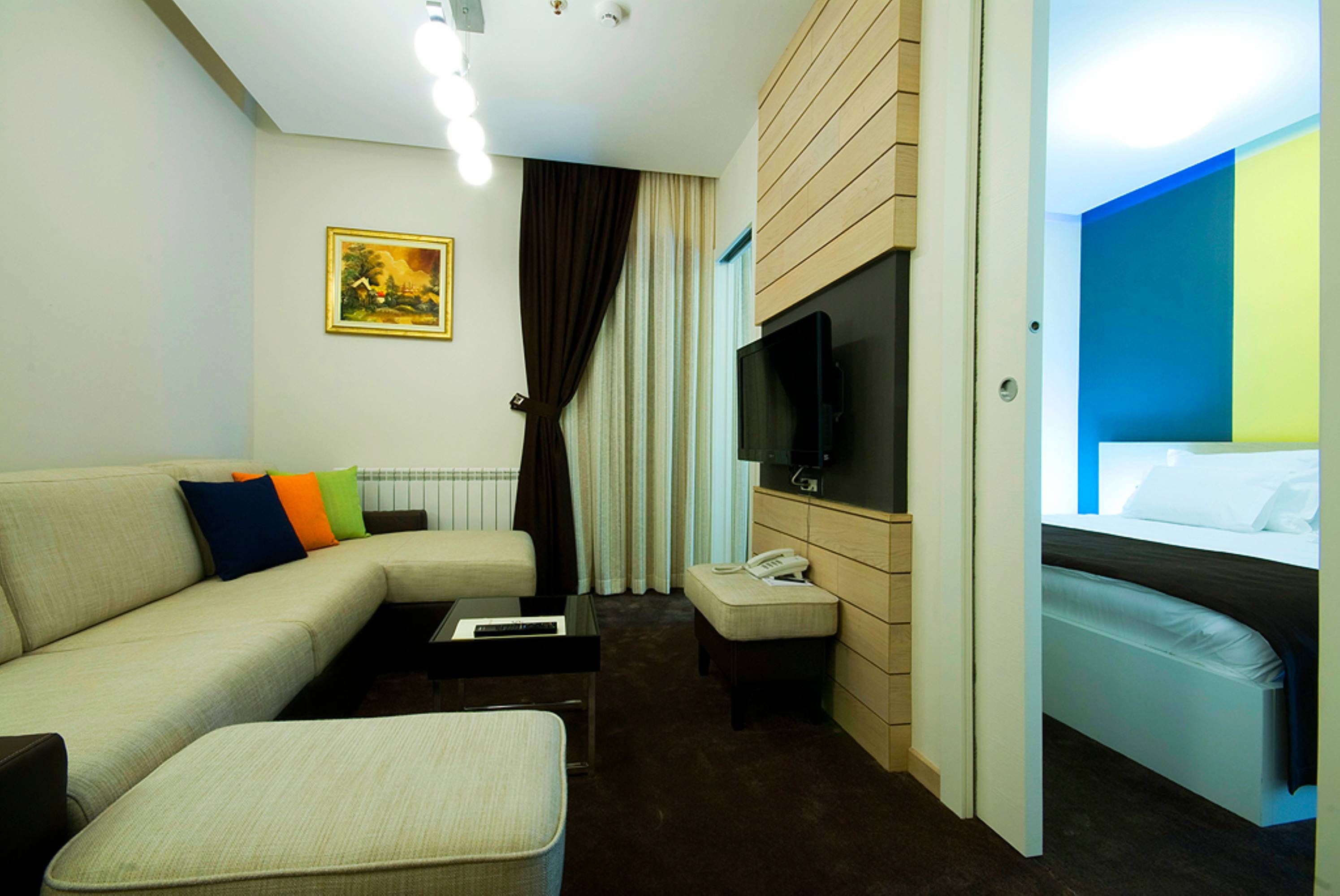 Una camera d'albergo con un divano, una TV, un comodino, un telefono e un letto.