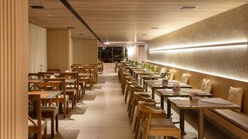 Um restaurante moderno com mesas e cadeiras de madeira, um balcão comprido e uma parede com textura.