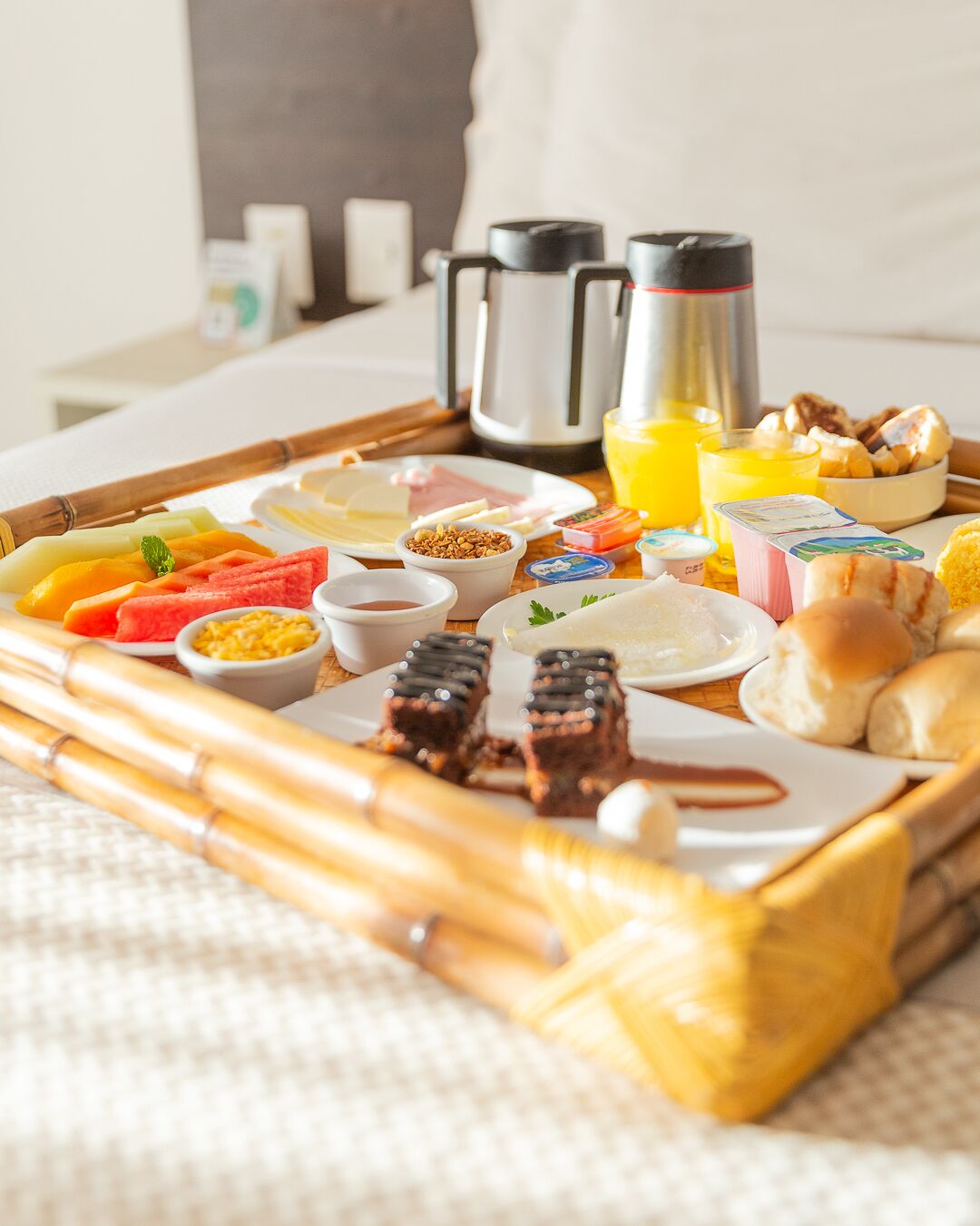 Un plateau de petit-déjeuner contenant divers aliments et boissons, notamment des fruits, des viennoiseries et du café.