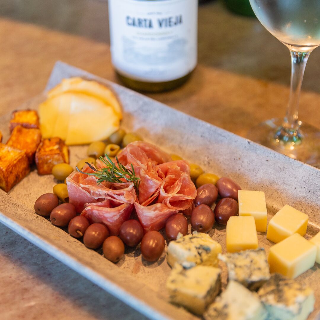 A charcuterie board with various meats, cheeses, and olives.