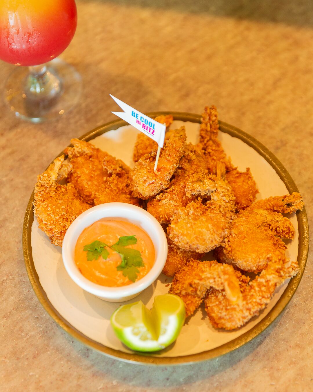 A plate of breaded and fried food with a dipping sauce and a lime wedge.