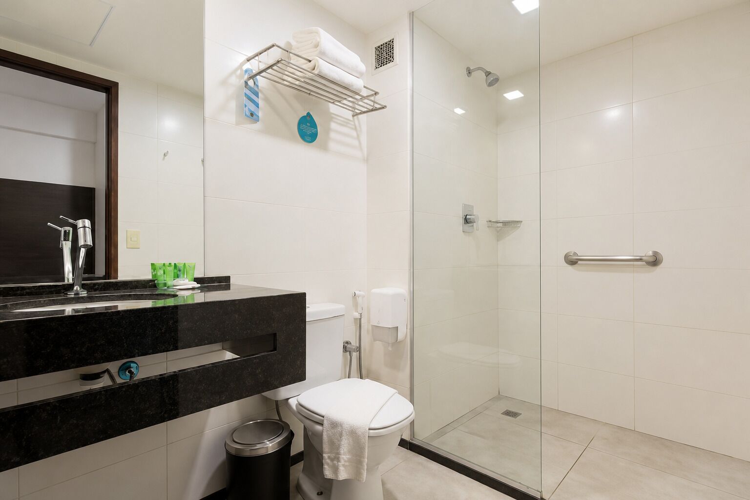 A modern bathroom with a glass shower enclosure, a black countertop sink, and a white toilet.