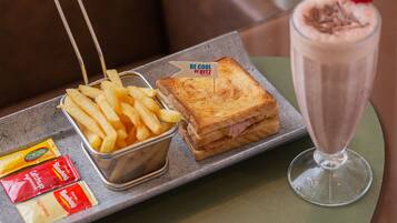 Una bandeja con un sándwich, papas fritas y una bebida sobre una mesa.