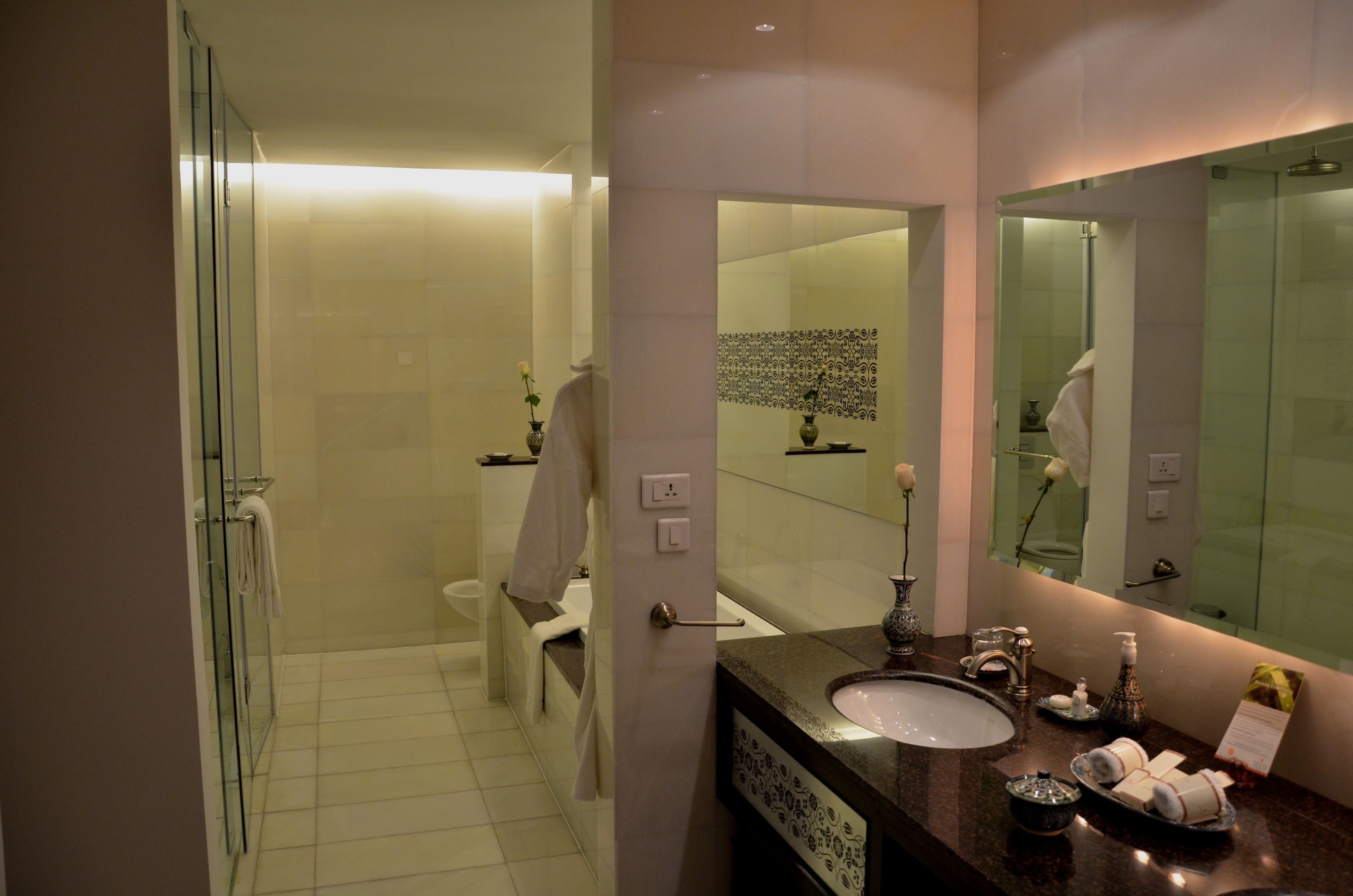 A modern bathroom with a glass shower enclosure, a white toilet, a sink with a mirror, and decorative items on the counter.