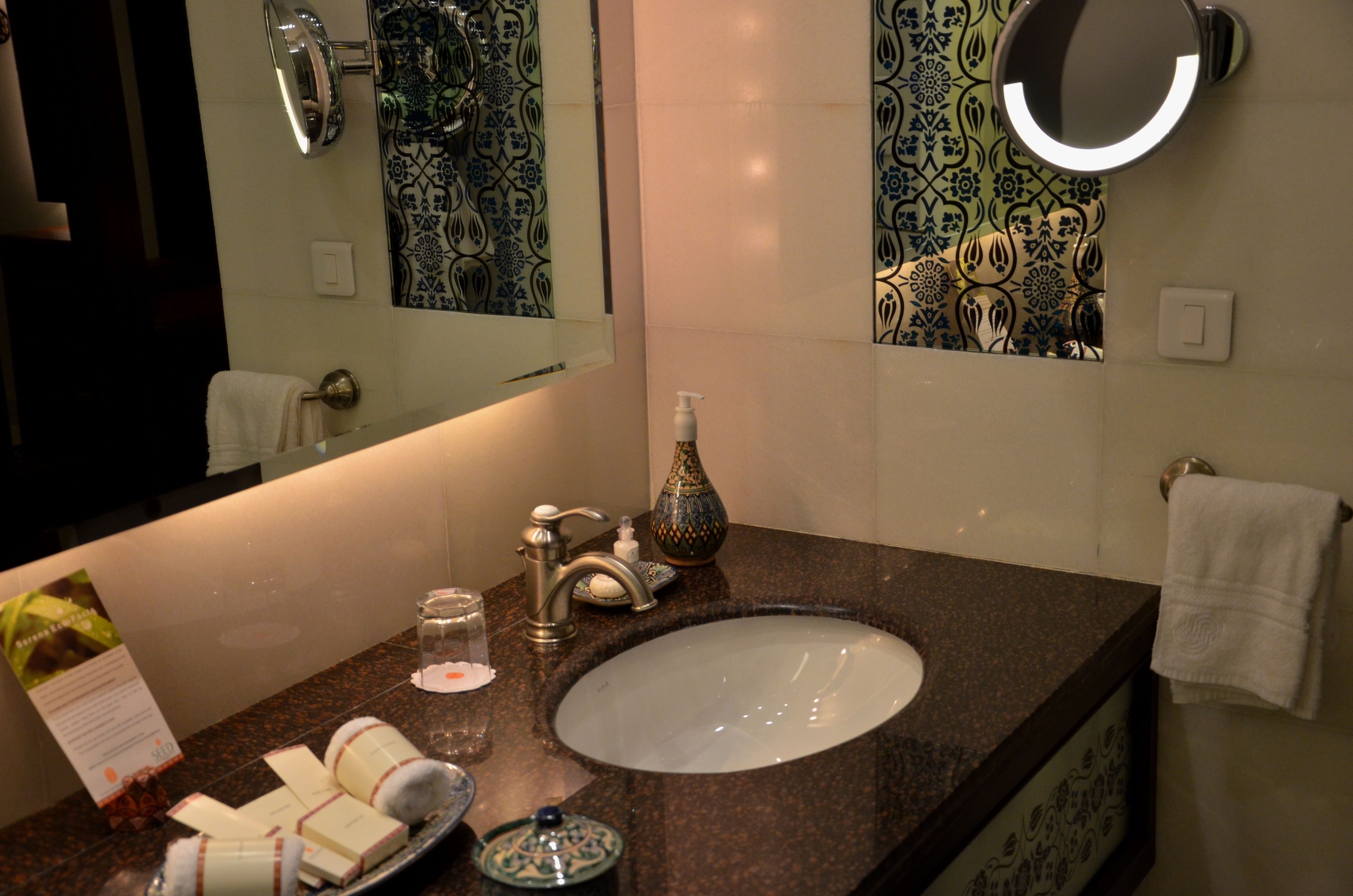 A bathroom with a sink, mirror, and decorative tiles.
