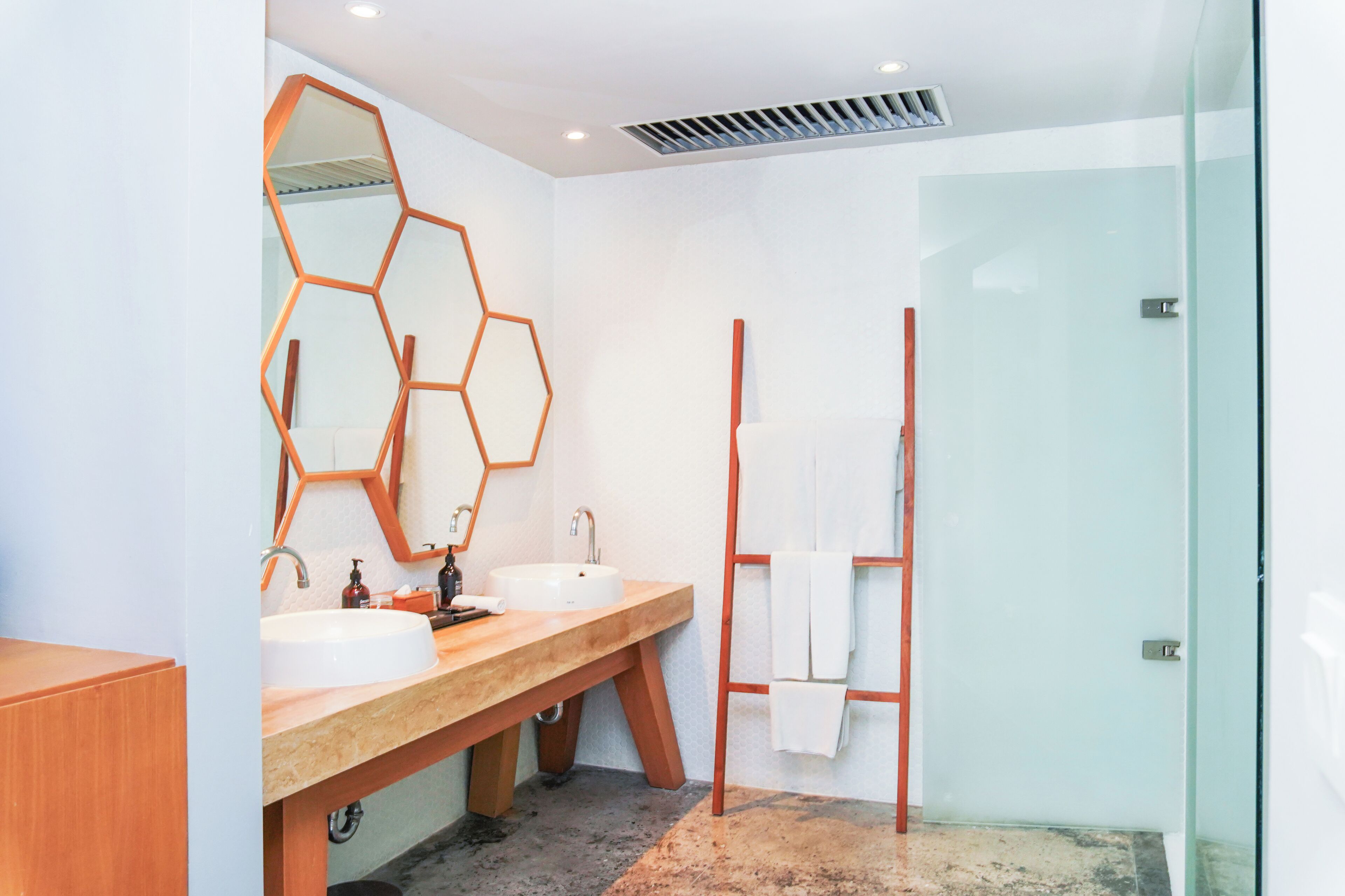 Un baño moderno con dos lavamanos, un espejo grande y una cabina de ducha con mampara de vidrio.