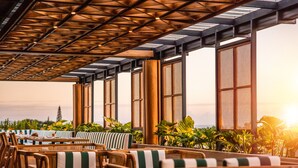 An outdoor seating area with wicker furniture and large windows. - Cross Paasha Bali Seminyak (Seminyak)