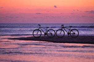 Un vélo garé sur une plage au coucher du soleil.