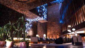 A lobby with a brick wall, seating area, and potted plants. - Cross Paasha Bali Seminyak (Seminyak)