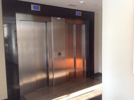 Um elevador moderno com portas metálicas e painel digital.