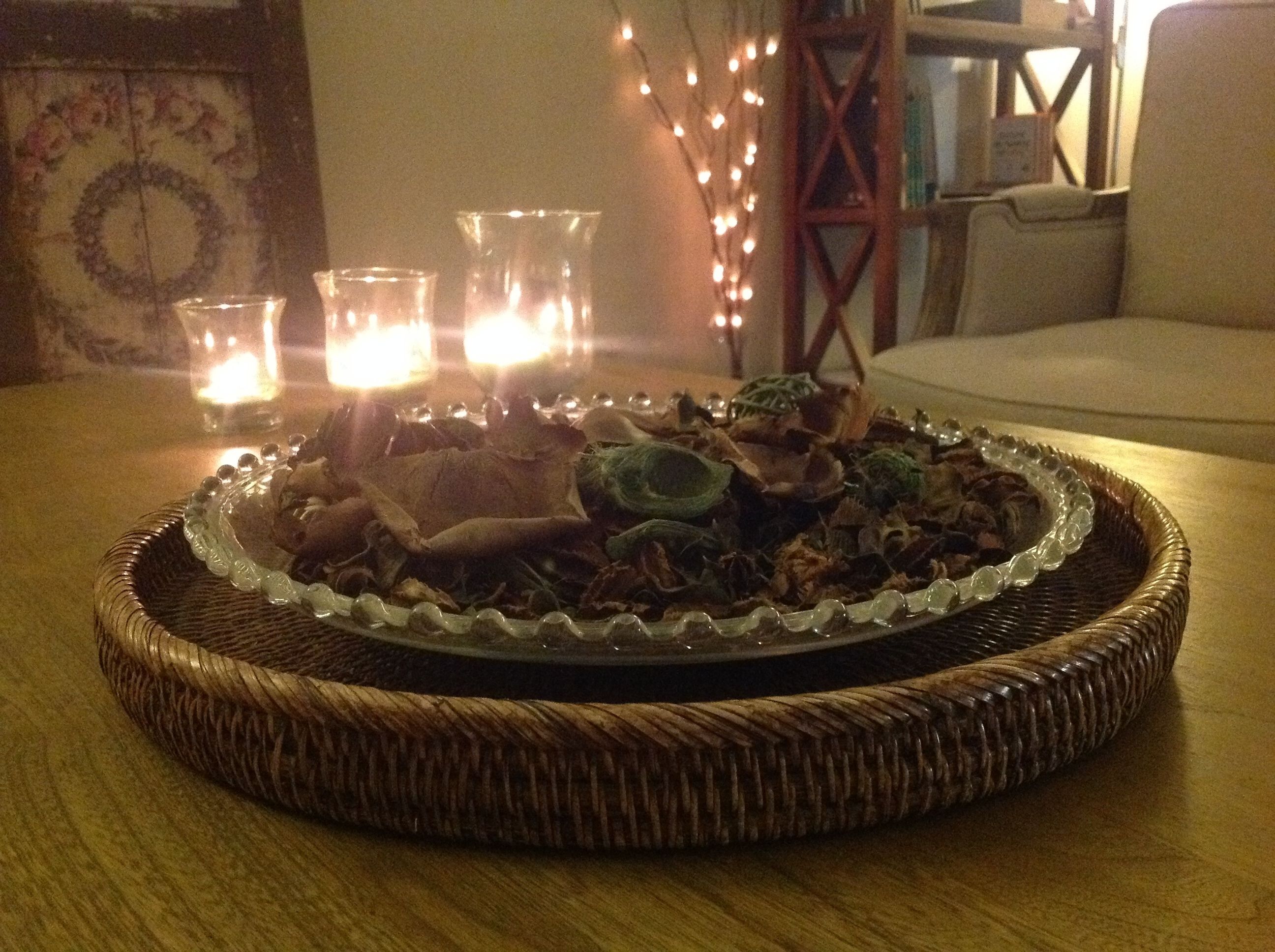 Een eettafel met een decoratief middelpunt, een rieten dienblad en een kandelaar met kaarsen.