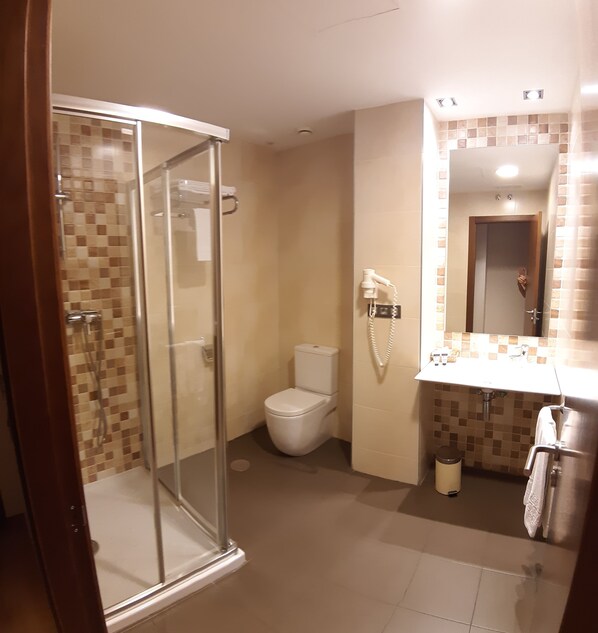 Une salle de bain avec une douche à parois de verre, des toilettes et un lavabo avec un miroir.