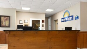 Una recepción con el letrero de Days Inn, certificados enmarcados y un cuadro en la pared.