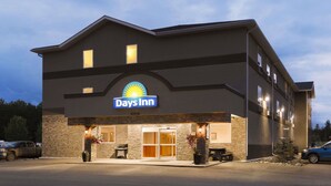 Un hotel Days Inn con fachada de piedra, una entrada amplia y mesas al aire libre.