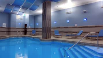 Piscina com degraus de acesso, rodeada por espreguiçadeiras e um design de teto moderno.