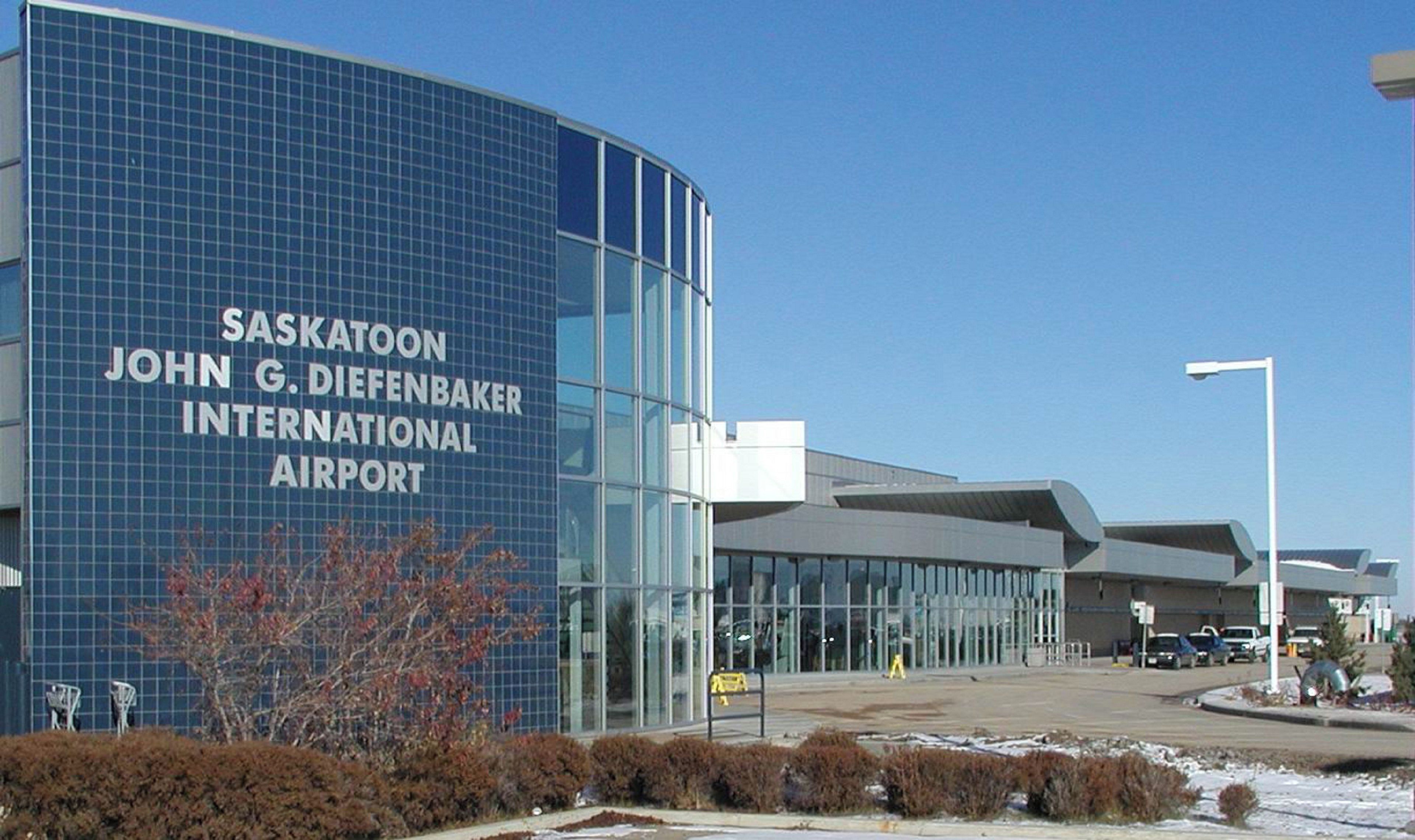 The exterior of Saskatoon John G. Diefenbaker International Airport with a modern glass facade and signage.