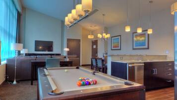 Une chambre d’hôtel équipée d’une table de billard, d’un canapé, d’une télévision et d’une kitchenette.