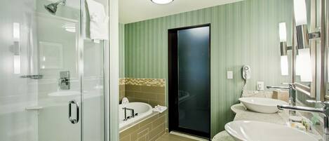 Un bany modern amb una cabina de dutxa de vidre, una banyera independent i dos rentabios amb miralls.