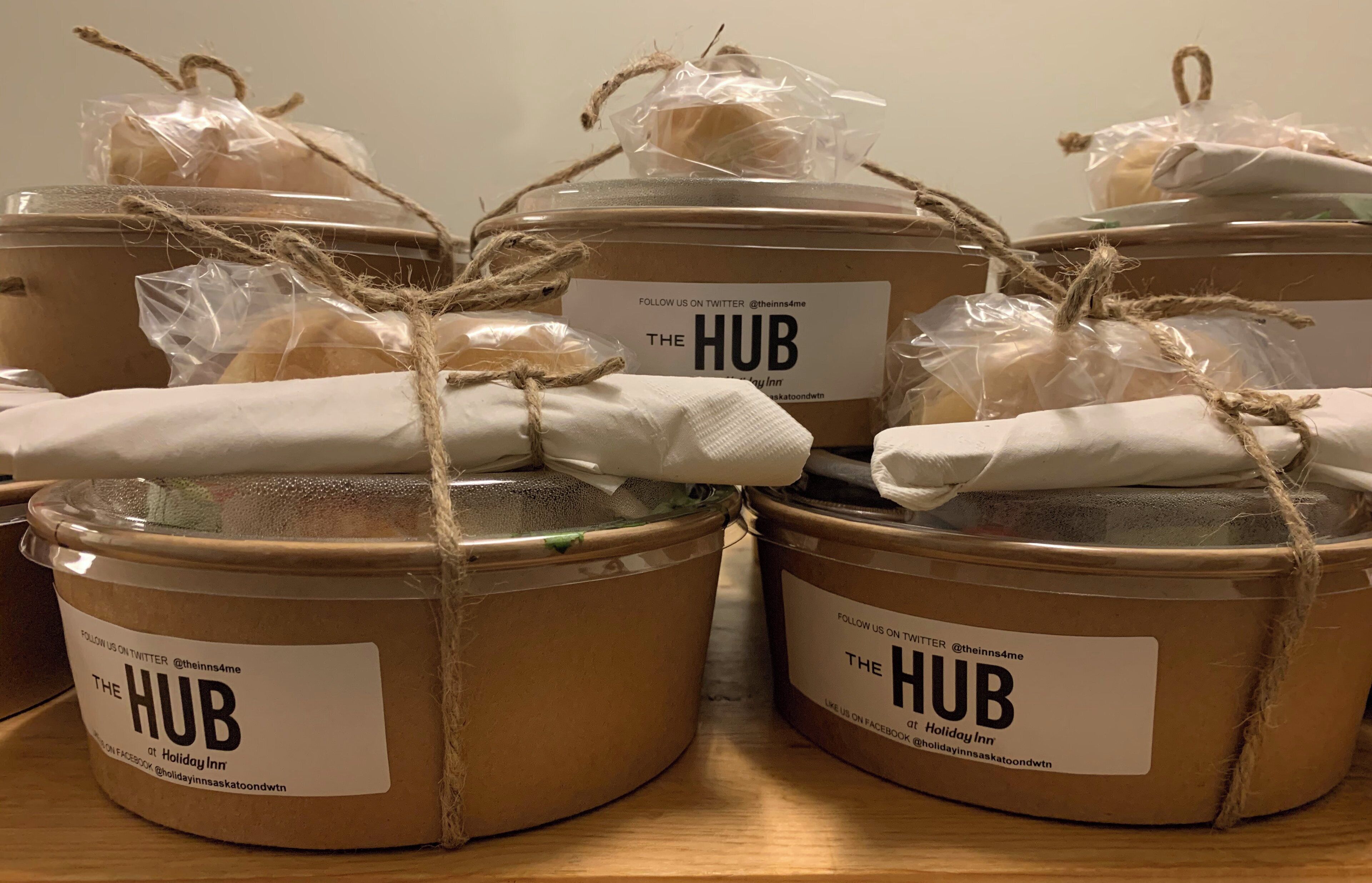 Several containers labeled "The HUB" at Holiday Inn, tied with twine and plastic bags.