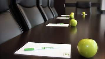 Una mesa de conferencias con papeles, un bolígrafo y una manzana verde encima.