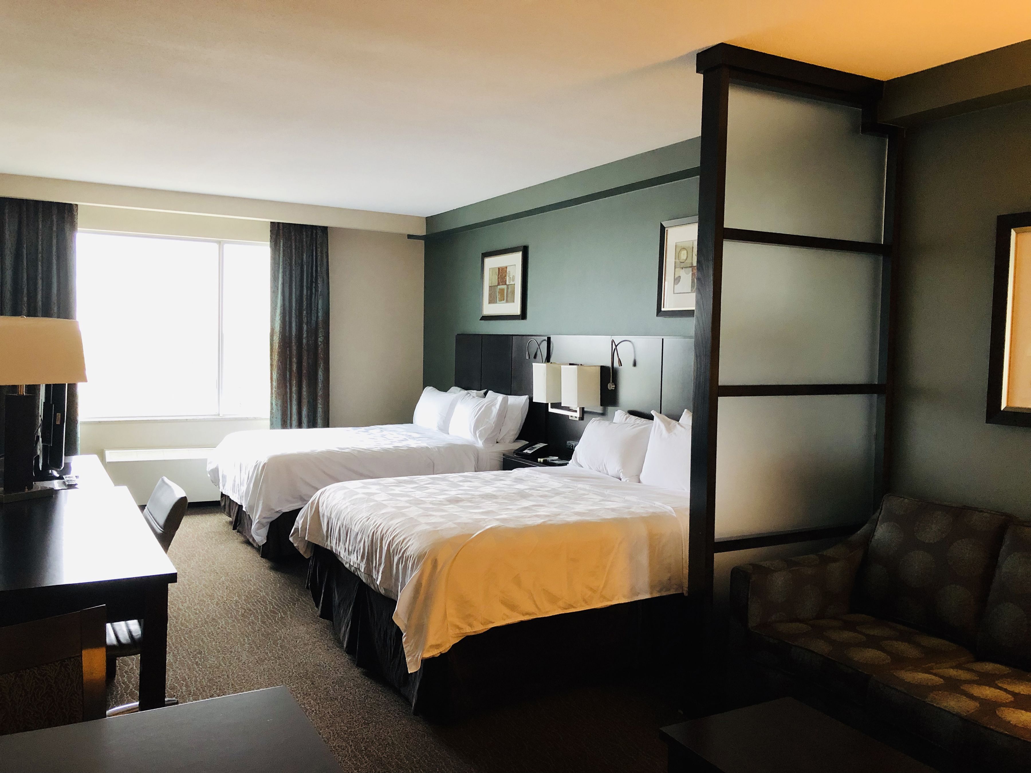 Une chambre d’hôtel avec deux lits, un bureau, une chaise et un canapé.