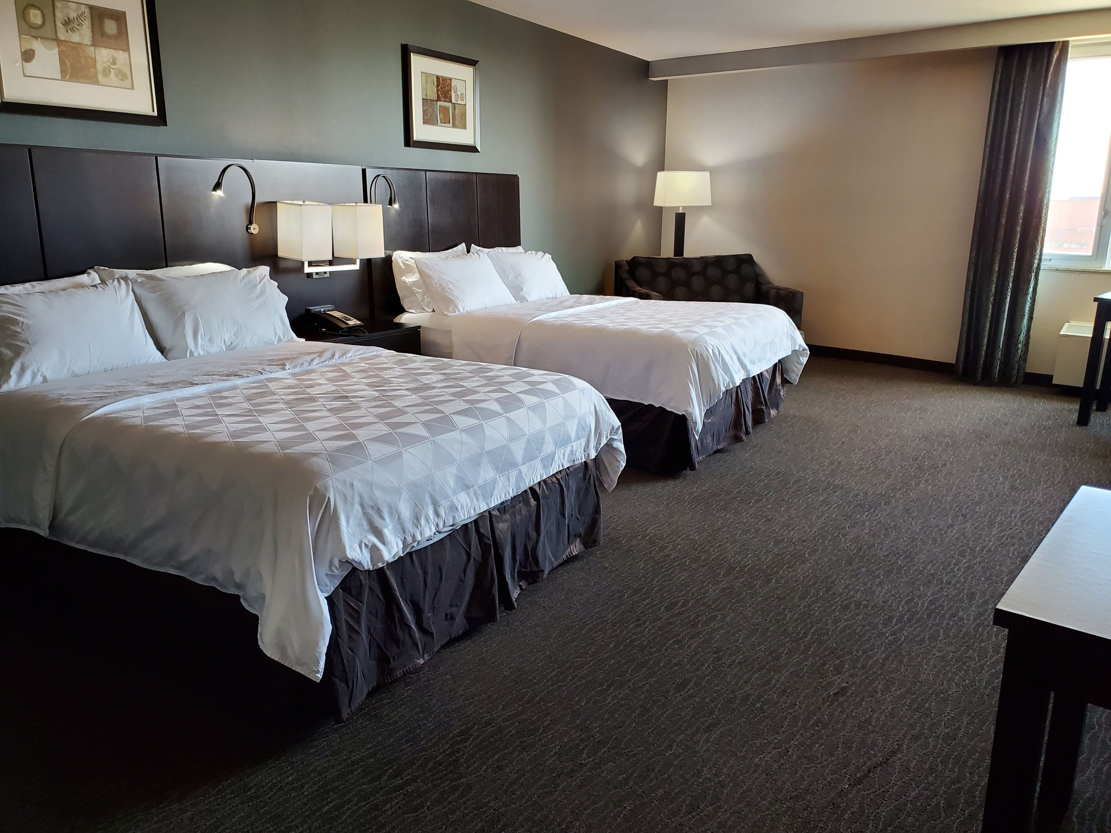 Habitación de hotel con dos camas, un escritorio y una lámpara.