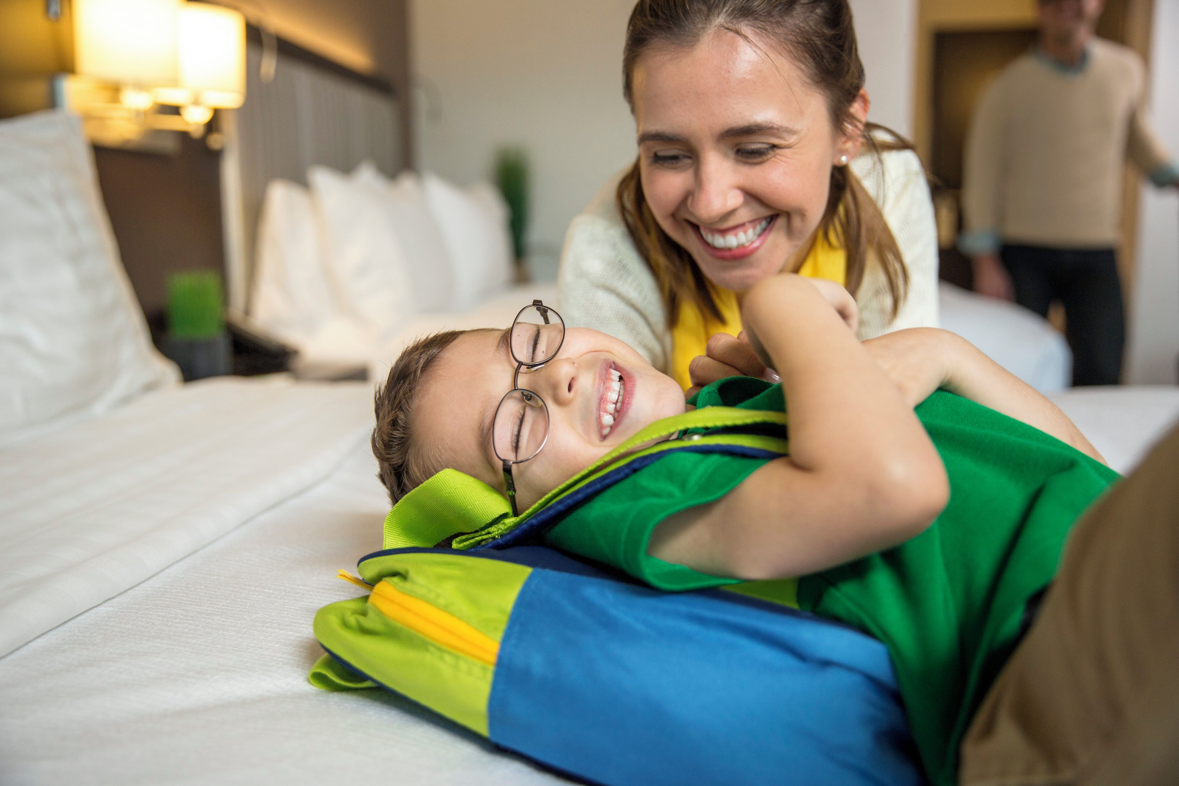 Una persona acostada en una cama con un almohadón y una manta.