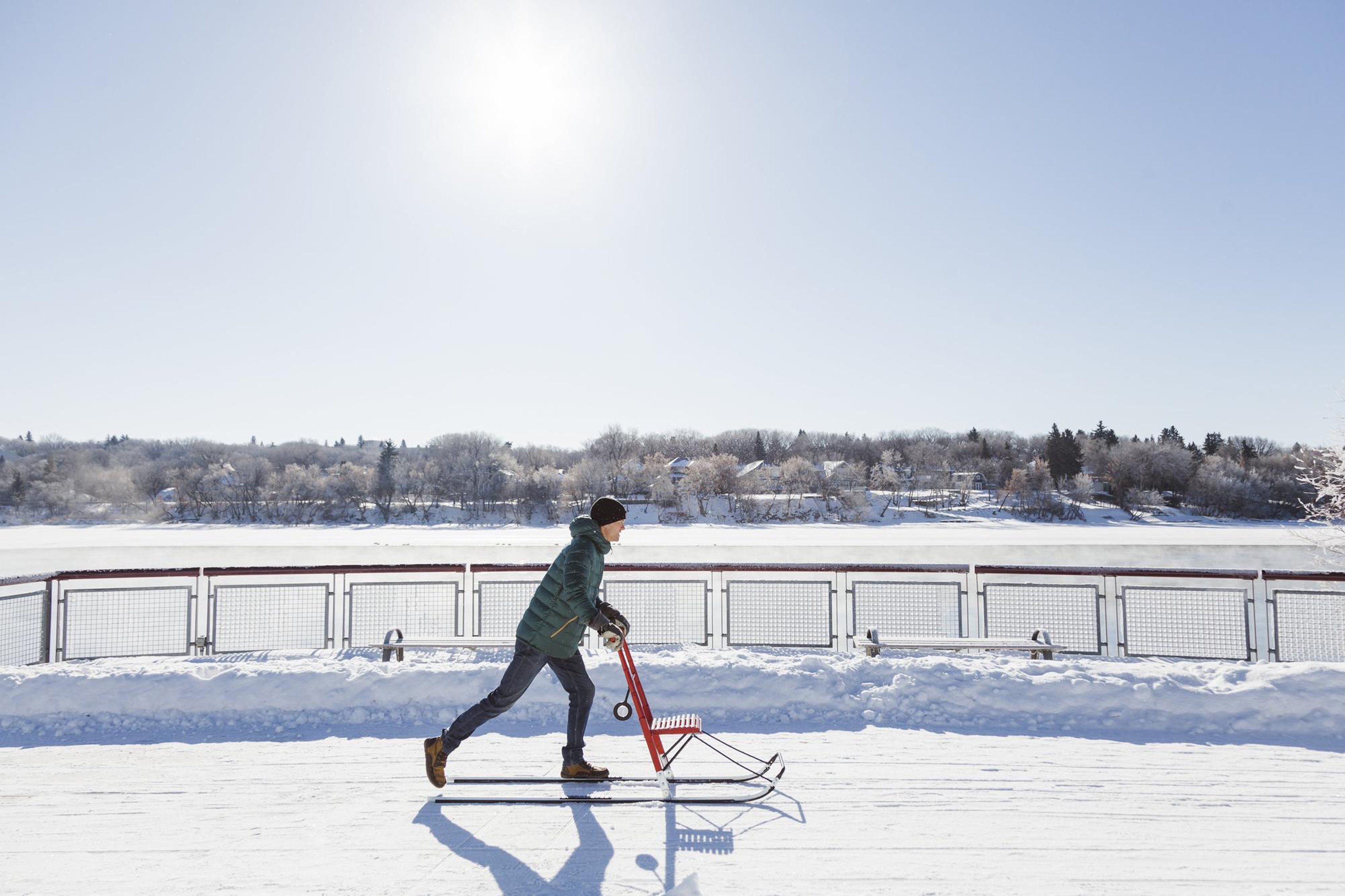 A person on a sled on a snowy surface with a fence in the background.