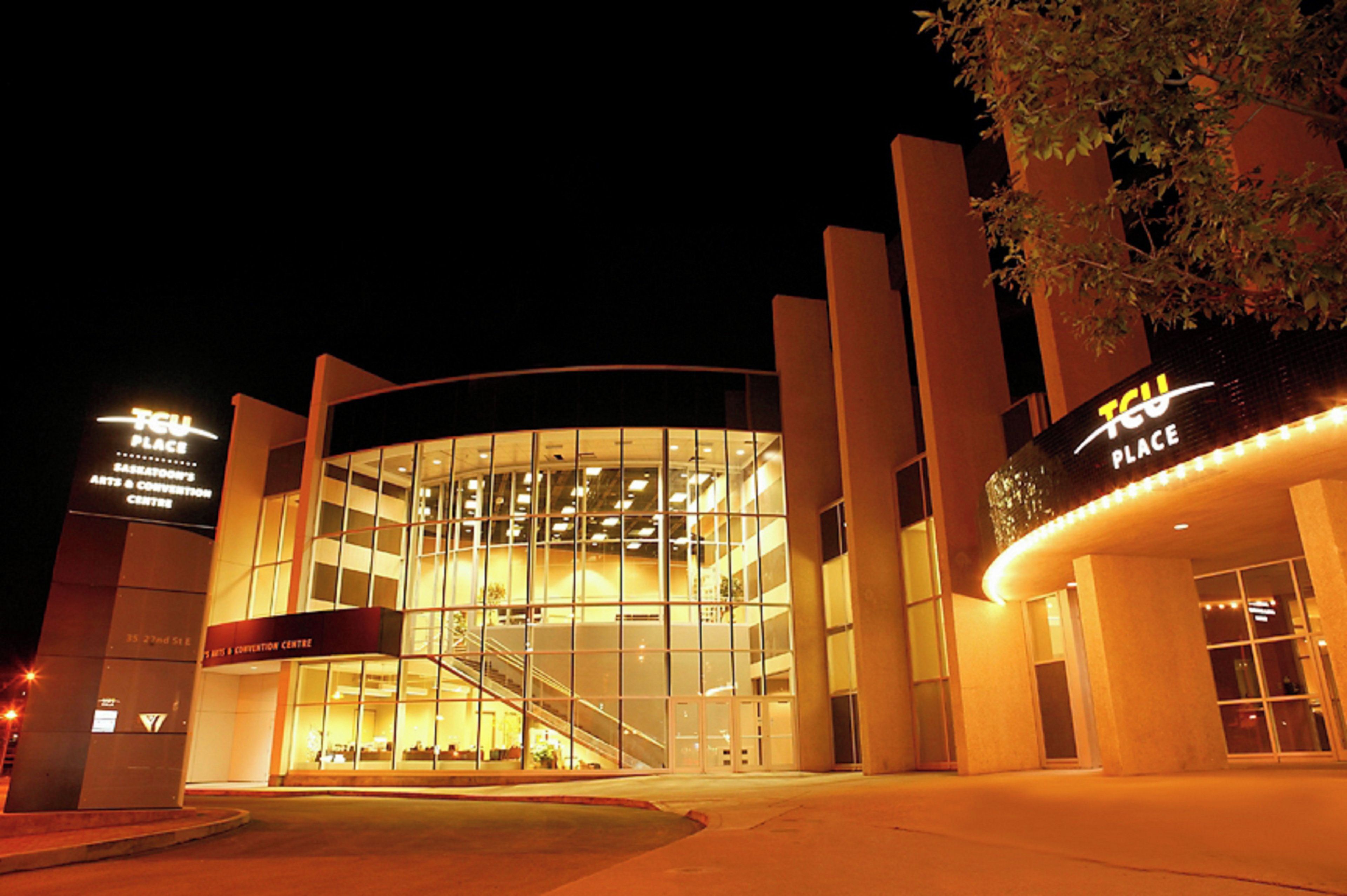 A modern building with a glass facade, a staircase leading to an upper level, and illuminated signage.