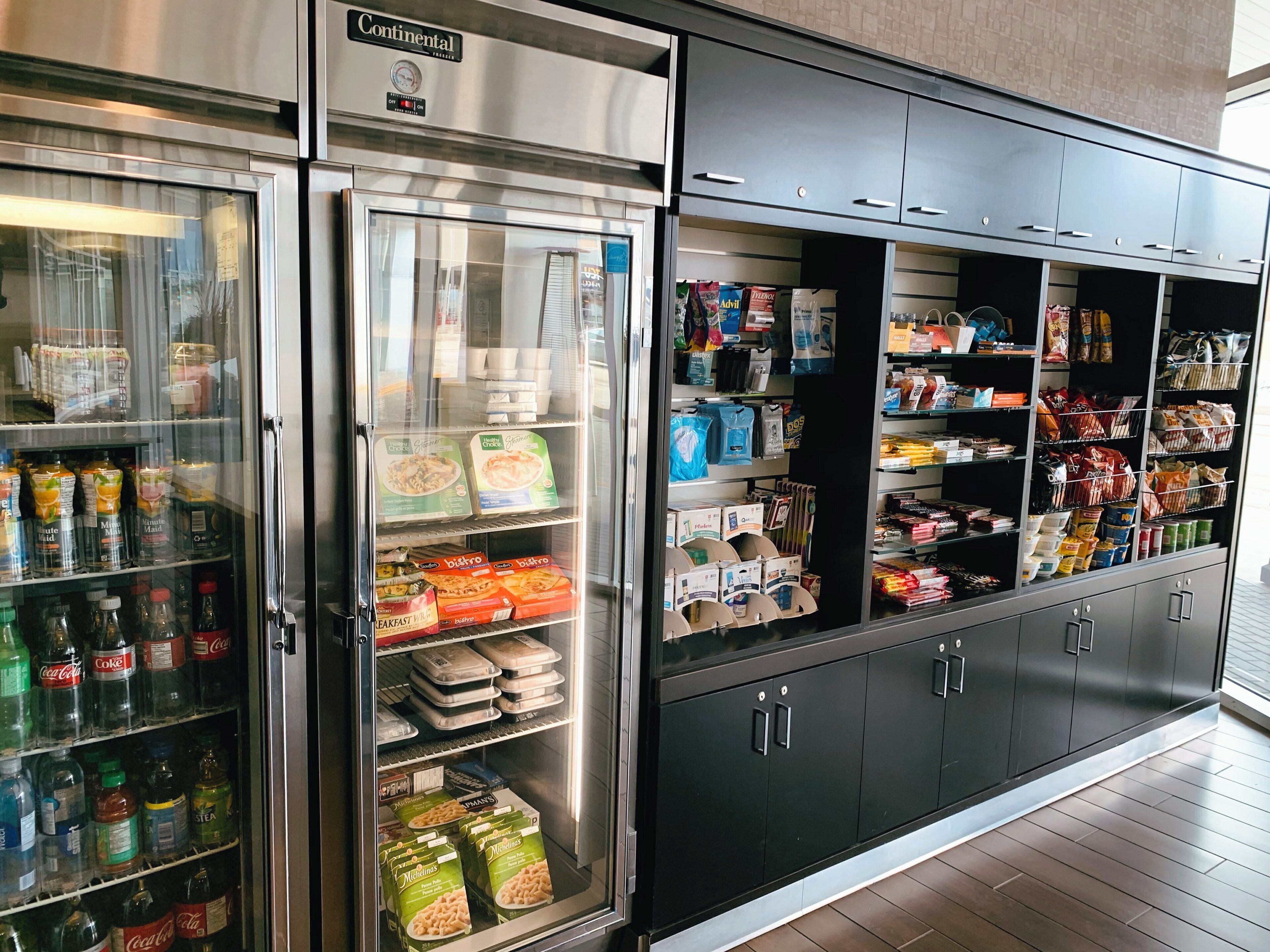 A refrigerated display case with various food items and beverages, including bottled drinks and packaged goods.