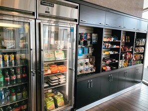 A refrigerated display case with various food items and beverages, including bottled drinks and packaged goods. - Holiday Inn Hotel & Suites Saskatoon Downtown by IHG (Saskatoon)