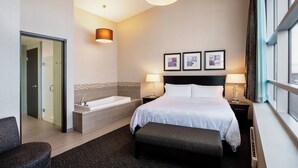 A hotel room with a large bed, a sitting area, a bathtub, and a window with a view. - Holiday Inn Hotel & Suites Saskatoon Downtown by IHG (Saskatoon)