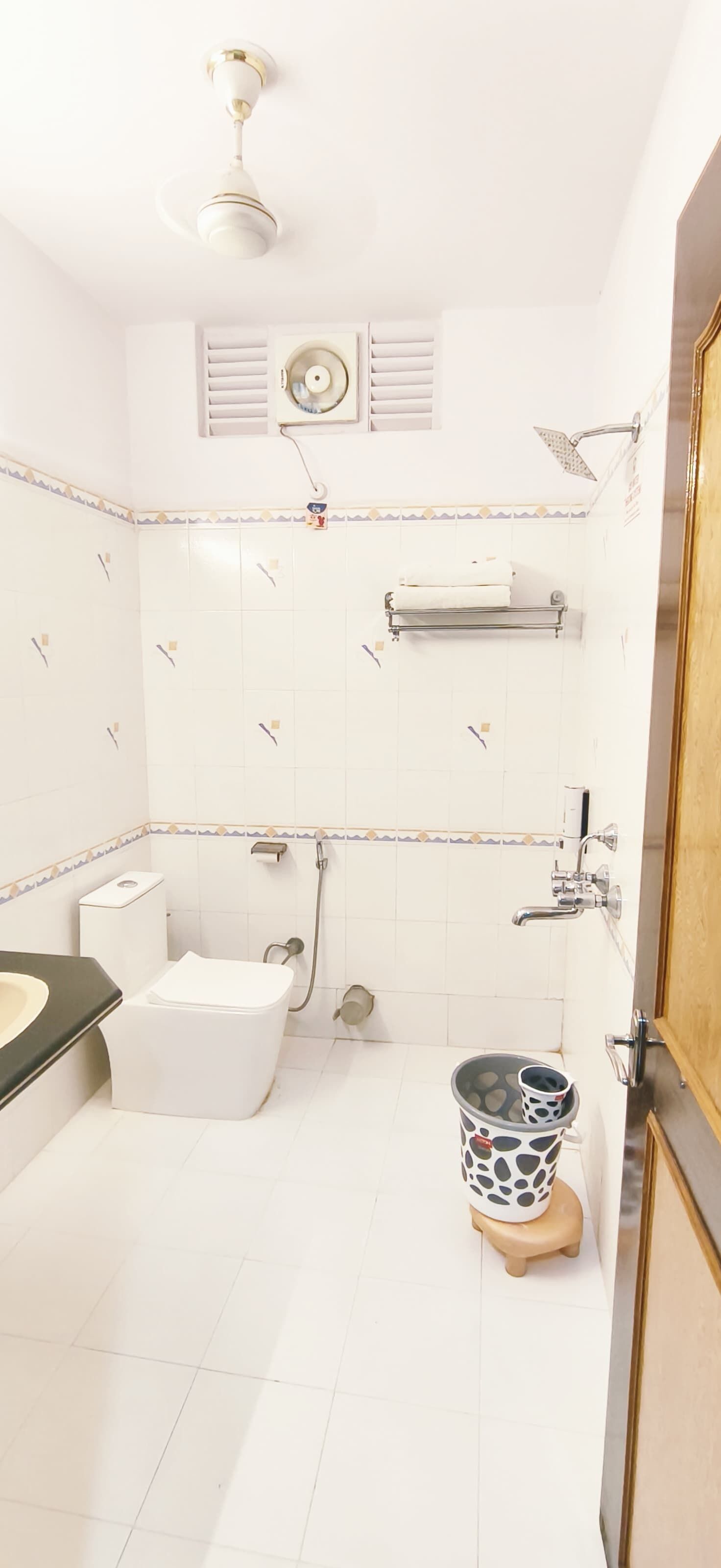 Un baño con inodoro, lavamanos, ducha y un cubo.