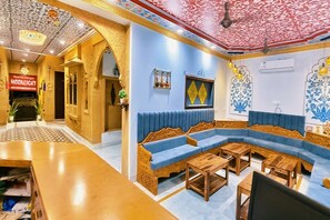 Un hall de hotel con un conjunto de sofá azul, mesas de madera y un techo estampado.
