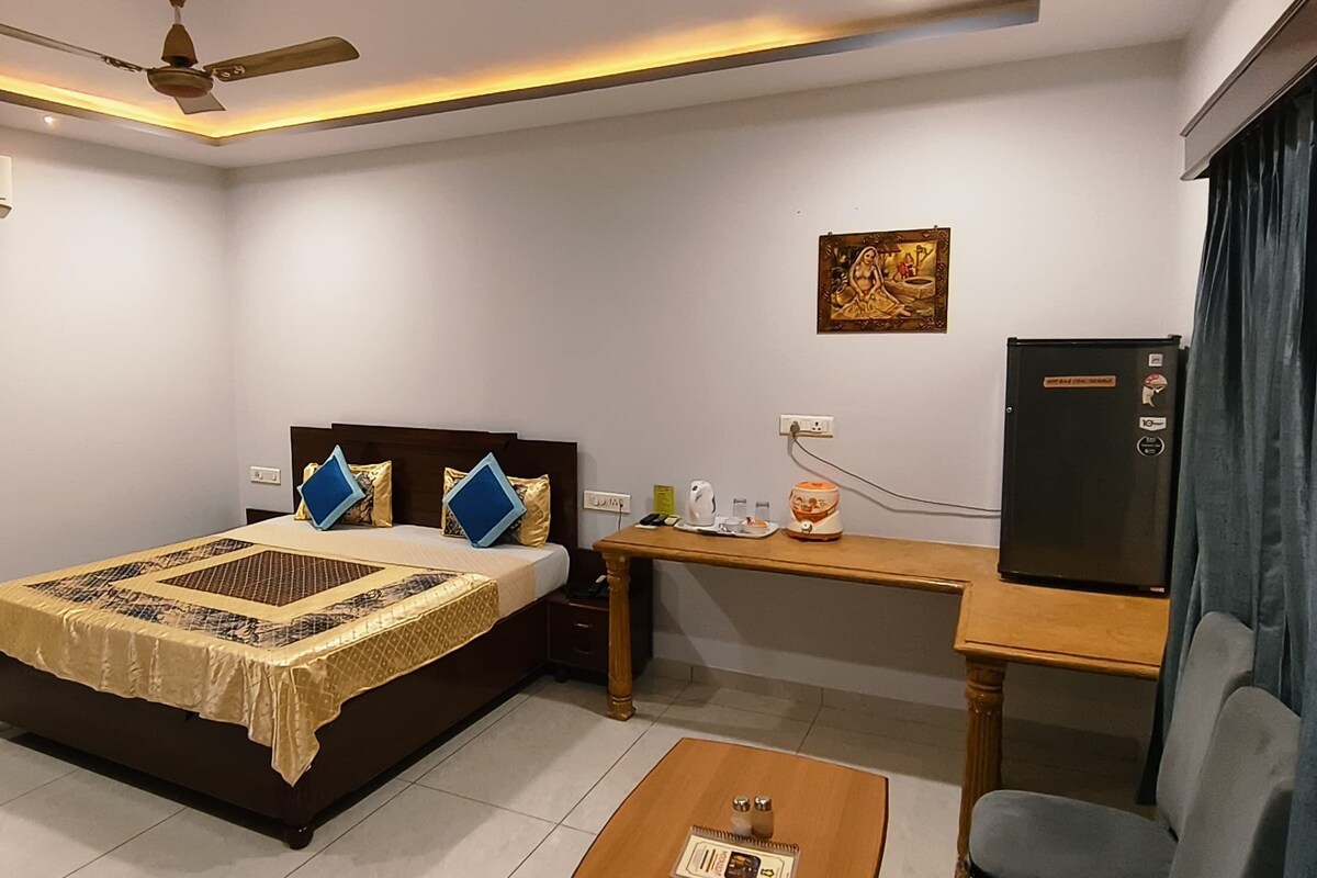 A bedroom with a bed, a desk, a chair, and a television.