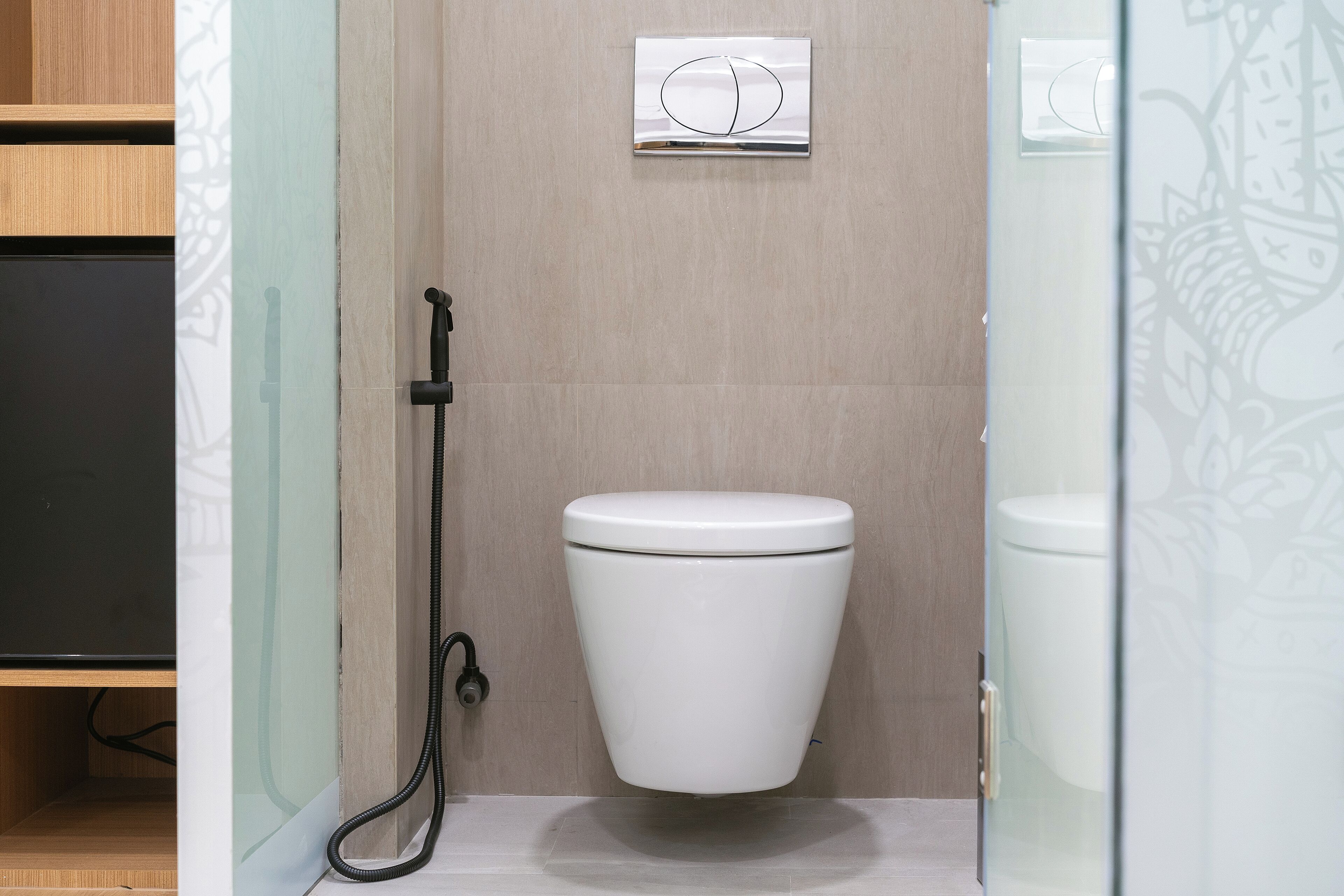 A modern bathroom with a white toilet, a shower area, and a glass partition.